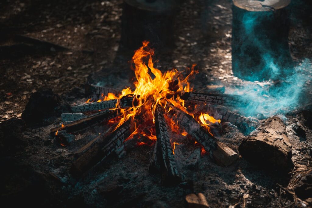 pexels photo 12267883 A vibrant campfire burning with glowing flames and smoke in a natural outdoor setting.
